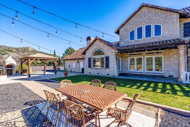 rear view of property featuring a gazebo, a lawn, and a patio area