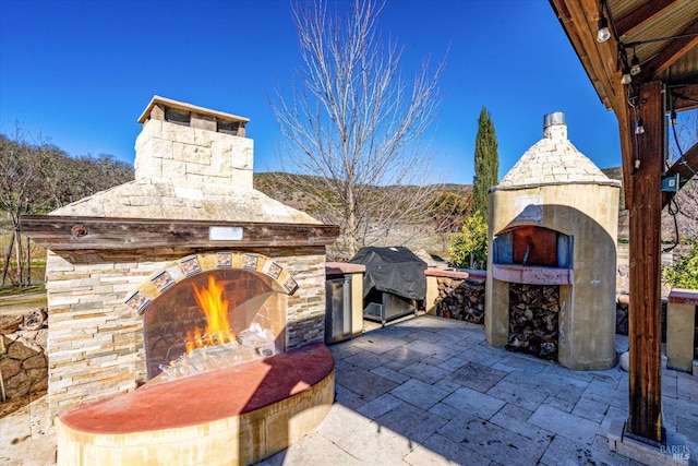 view of patio featuring a grill and an outdoor stone fireplace