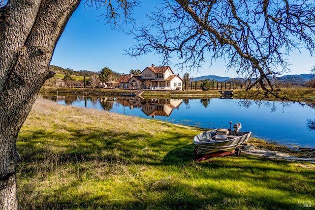 dock area featuring a water and mountain view and a lawn