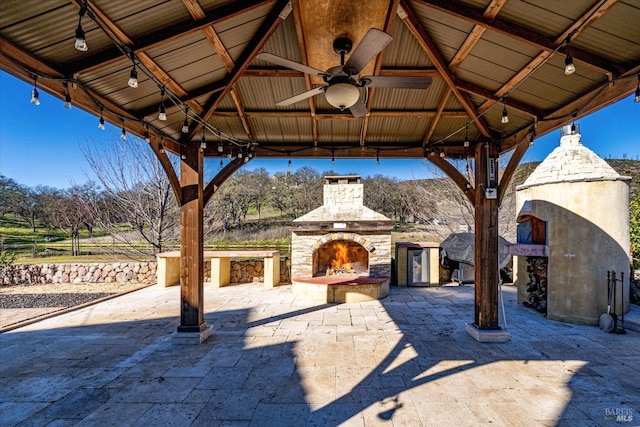 view of patio with a gazebo, ceiling fan, and an outdoor stone fireplace