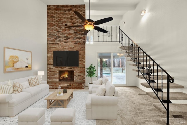 carpeted living room with a fireplace, ceiling fan, and a high ceiling