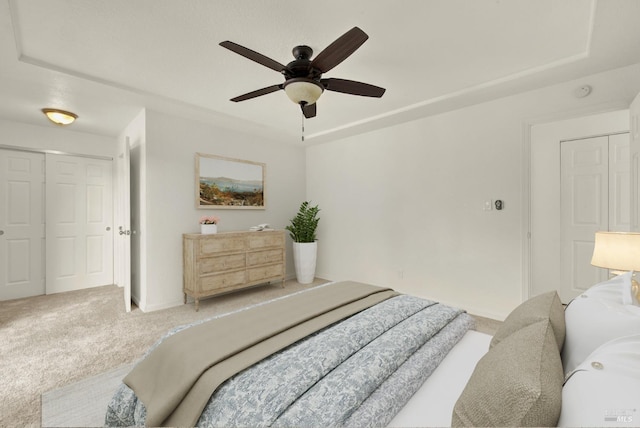 carpeted bedroom with a raised ceiling, ceiling fan, and a closet