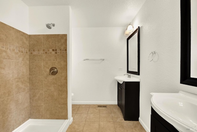 bathroom with vanity, a tile shower, and tile patterned floors