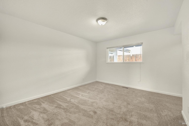 empty room with carpet flooring and a textured ceiling