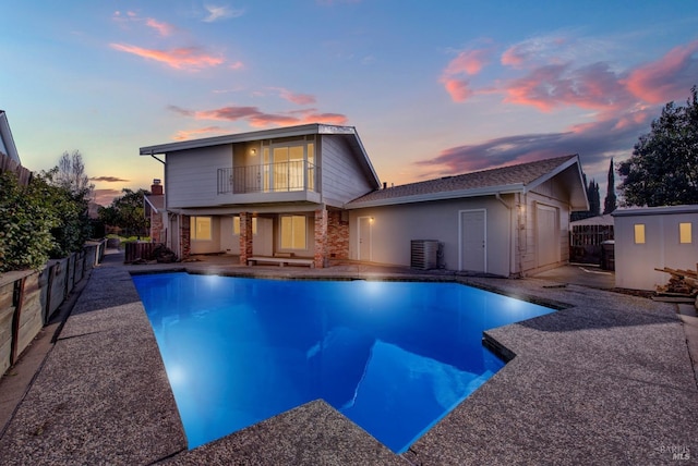 pool at dusk with a patio, an outdoor structure, and central AC