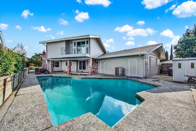 rear view of house featuring a fenced in pool, a balcony, and central AC unit