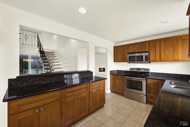 kitchen with sink, stainless steel appliances, and dark stone counters