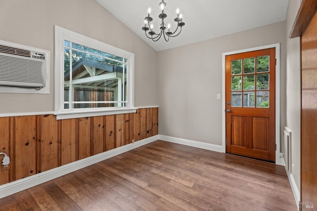 interior space featuring baseboards, an inviting chandelier, vaulted ceiling, light wood-style floors, and a wall mounted AC