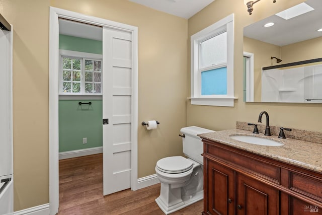 bathroom featuring vanity, toilet, hardwood / wood-style floors, and a skylight