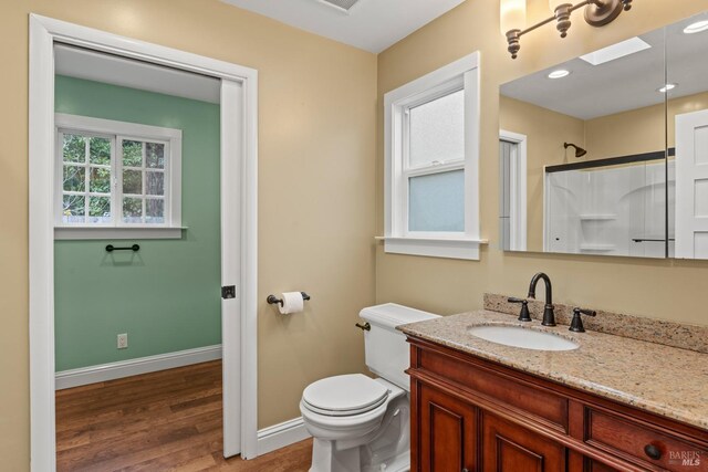 bathroom featuring hardwood / wood-style flooring, vanity, toilet, and a shower