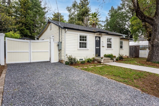 view of front of home featuring driveway, crawl space, a shingled roof, and fence