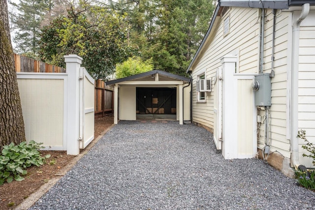 exterior space featuring an outbuilding, fence, driveway, and a detached garage