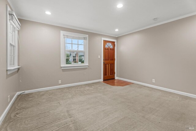 foyer entrance with ornamental molding and light colored carpet