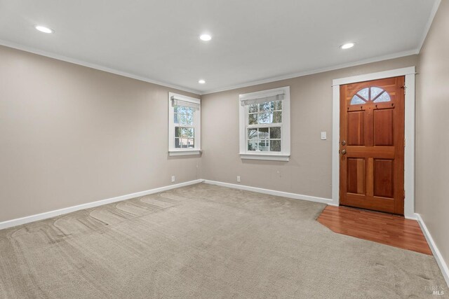 foyer entrance with ornamental molding and carpet floors