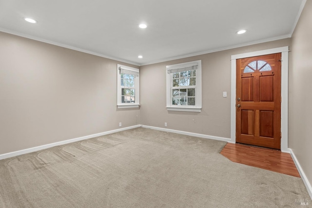 carpeted foyer featuring baseboards, crown molding, and recessed lighting