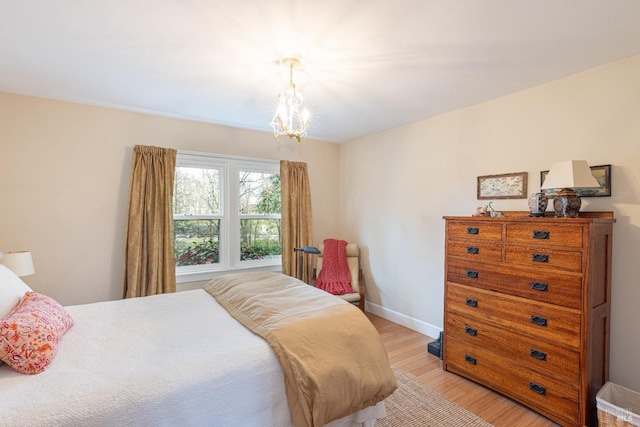 bedroom with light hardwood / wood-style flooring and a chandelier