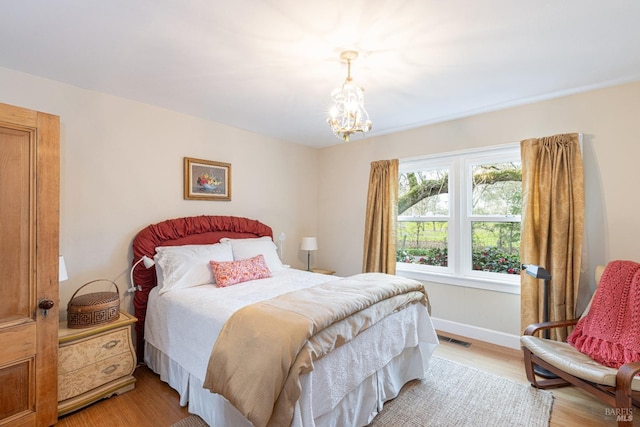 bedroom with an inviting chandelier and light hardwood / wood-style floors