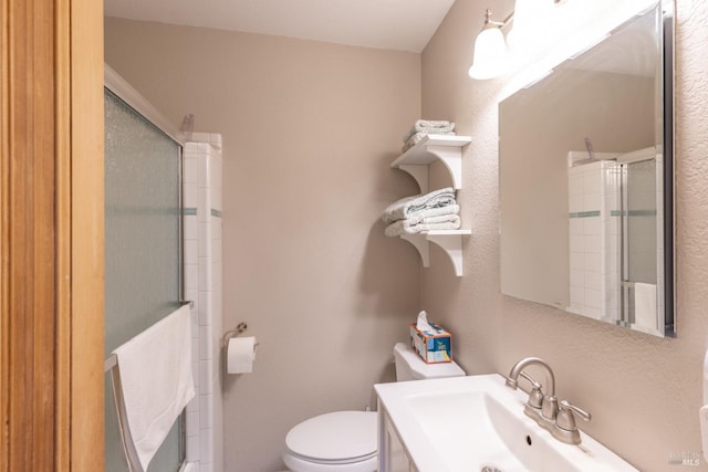 bathroom featuring sink, toilet, and a shower with door