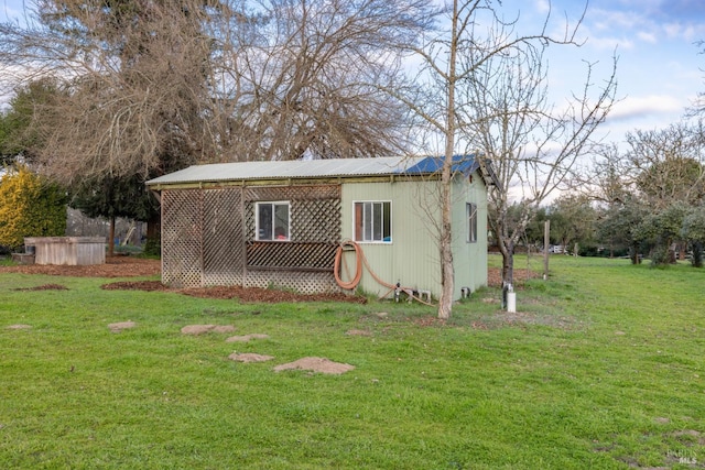 view of side of home with an outdoor structure and a yard