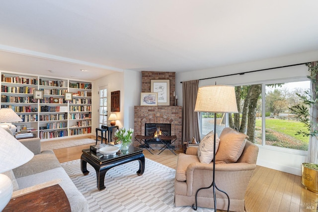 living room with a brick fireplace and light hardwood / wood-style flooring