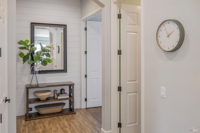 hall with light wood-type flooring and wood walls