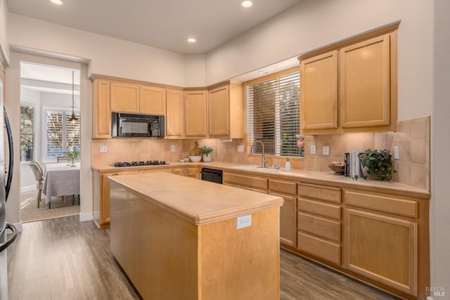 kitchen with light brown cabinetry, sink, black appliances, and a kitchen island