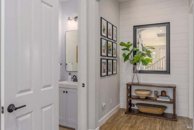 hall with sink, wooden walls, and light hardwood / wood-style floors