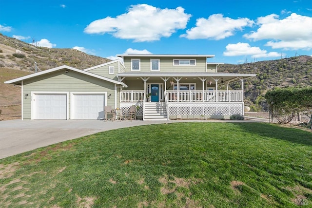 view of front of house with a mountain view, covered porch, a garage, driveway, and a front lawn