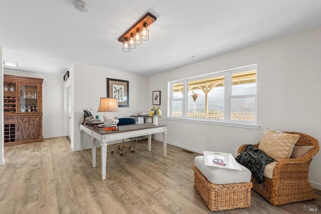 office space featuring baseboards, visible vents, and wood finished floors