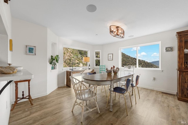 dining room with an inviting chandelier, light wood-style flooring, and baseboards