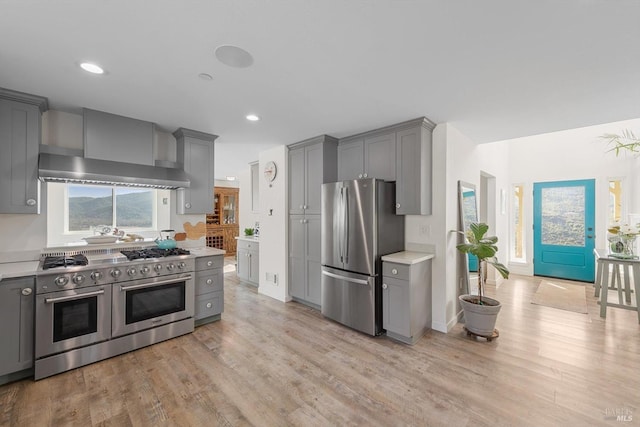 kitchen with wall chimney exhaust hood, appliances with stainless steel finishes, gray cabinets, and light countertops