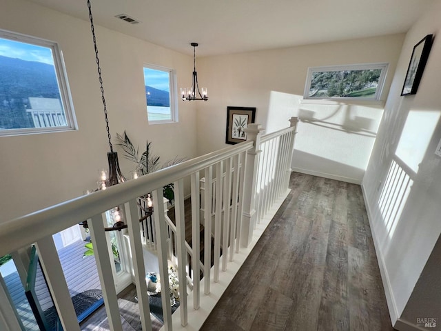 hall with a notable chandelier, an upstairs landing, baseboards, visible vents, and dark wood finished floors