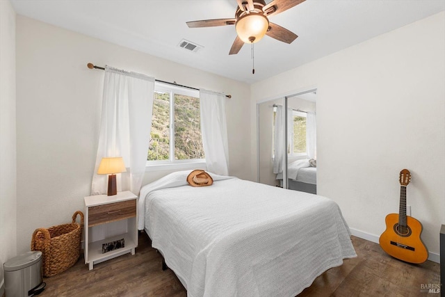 bedroom with dark wood-style flooring, a closet, visible vents, ceiling fan, and baseboards