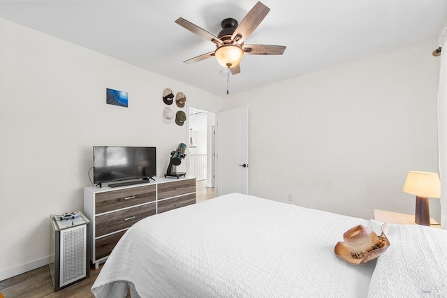 bedroom with ceiling fan, baseboards, and wood finished floors