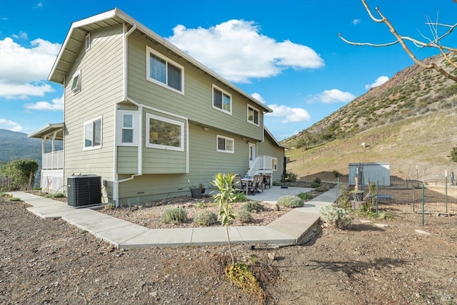 rear view of house featuring fence, a mountain view, and central AC