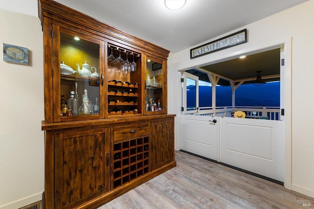 wine area featuring light wood-style flooring and a textured ceiling