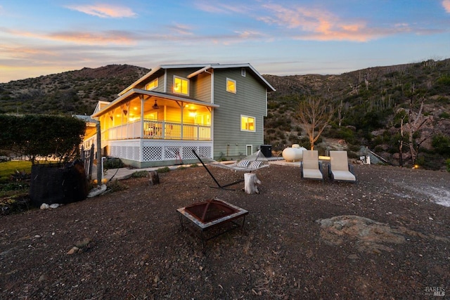 front of property at dusk featuring an outdoor fire pit, covered porch, and a mountain view