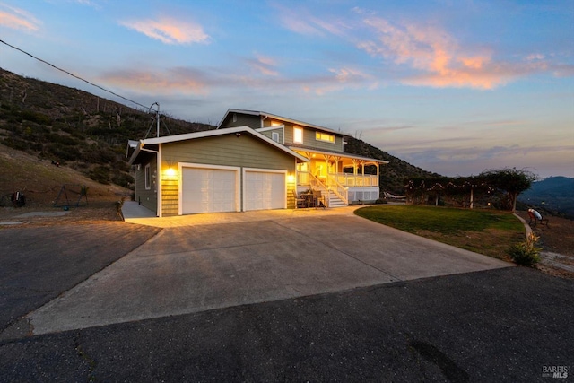 view of front of property featuring a porch, a garage, driveway, stairway, and a front lawn