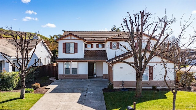 mediterranean / spanish-style home with a tile roof, a front lawn, driveway, fence, and stucco siding