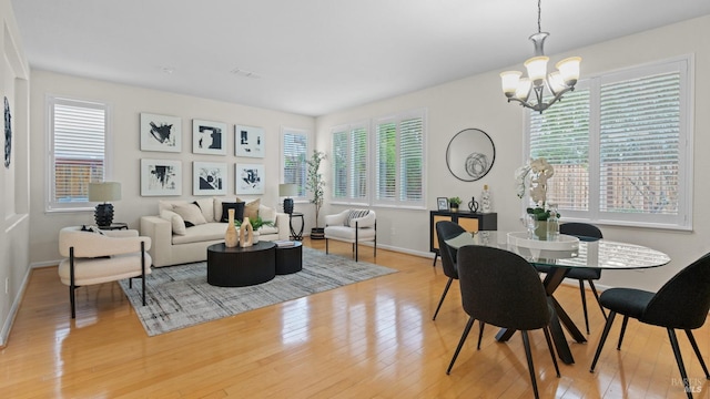 dining area featuring an inviting chandelier, a wealth of natural light, and light hardwood / wood-style floors