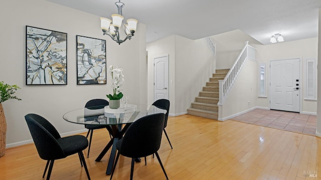 dining room with baseboards, an inviting chandelier, stairs, and hardwood / wood-style floors