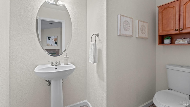 bathroom featuring toilet and baseboards