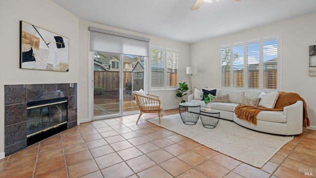 tiled living area featuring baseboards, a fireplace, and ceiling fan