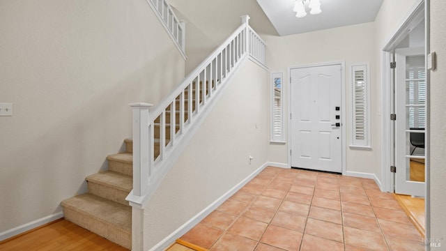 foyer entrance featuring baseboards, stairs, and light tile patterned floors