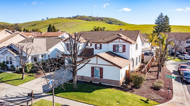 exterior space with a tile roof, concrete driveway, a residential view, and stucco siding