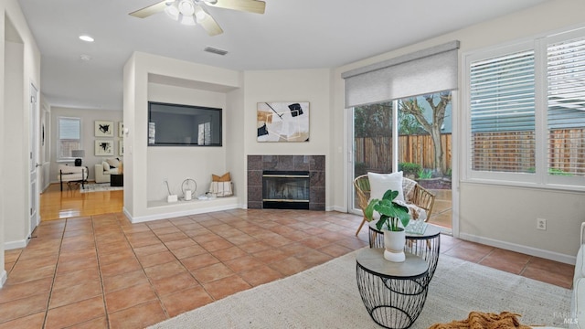 tiled living room with a tiled fireplace and ceiling fan