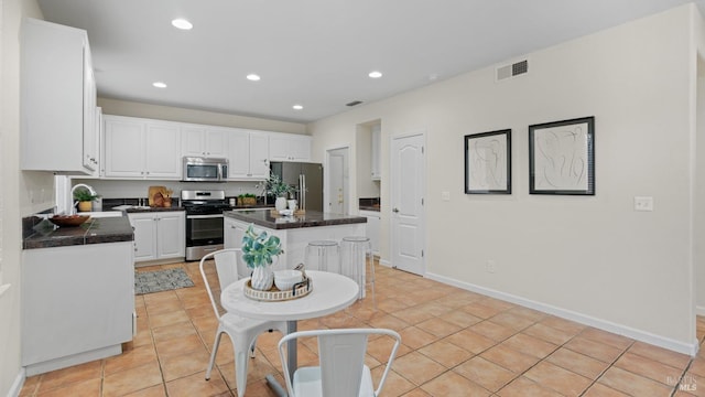 kitchen featuring sink, white cabinetry, a center island, light tile patterned floors, and stainless steel appliances