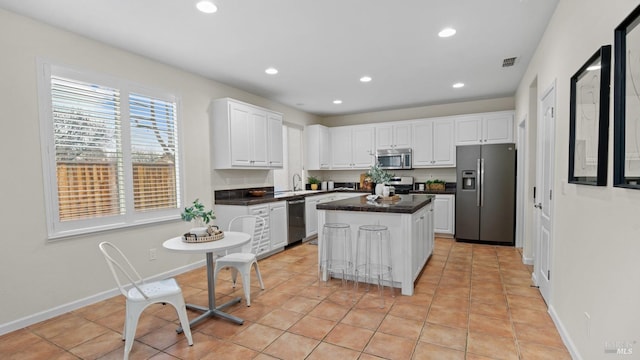 kitchen featuring dark countertops, appliances with stainless steel finishes, white cabinetry, visible vents, and a kitchen island