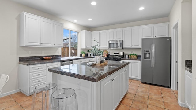 kitchen featuring a center island, a sink, light tile patterned floors, stainless steel appliances, and white cabinetry