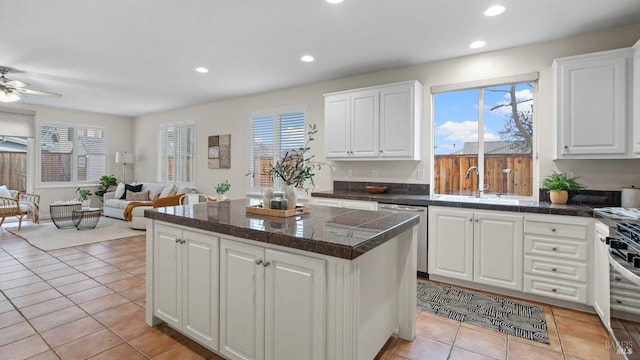 kitchen featuring light tile patterned flooring, sink, dishwasher, a kitchen island, and white cabinets